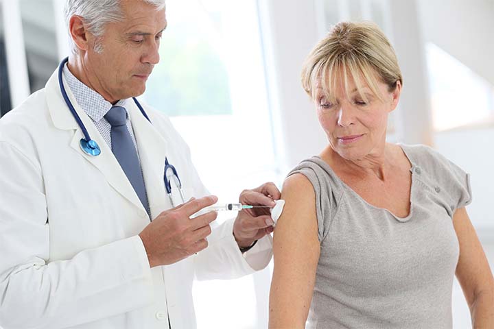 An adult  blonde woman receiving a vaccine on her forearm