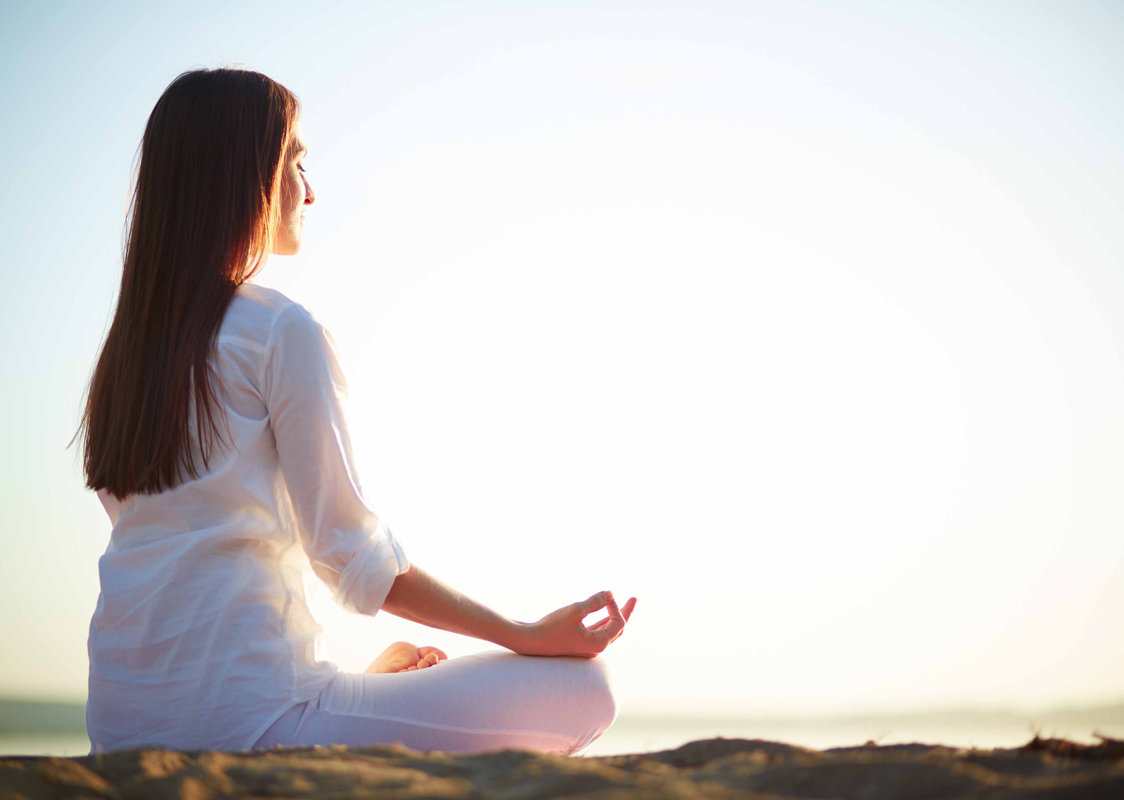 Woman in a white shirt meditating outdoors