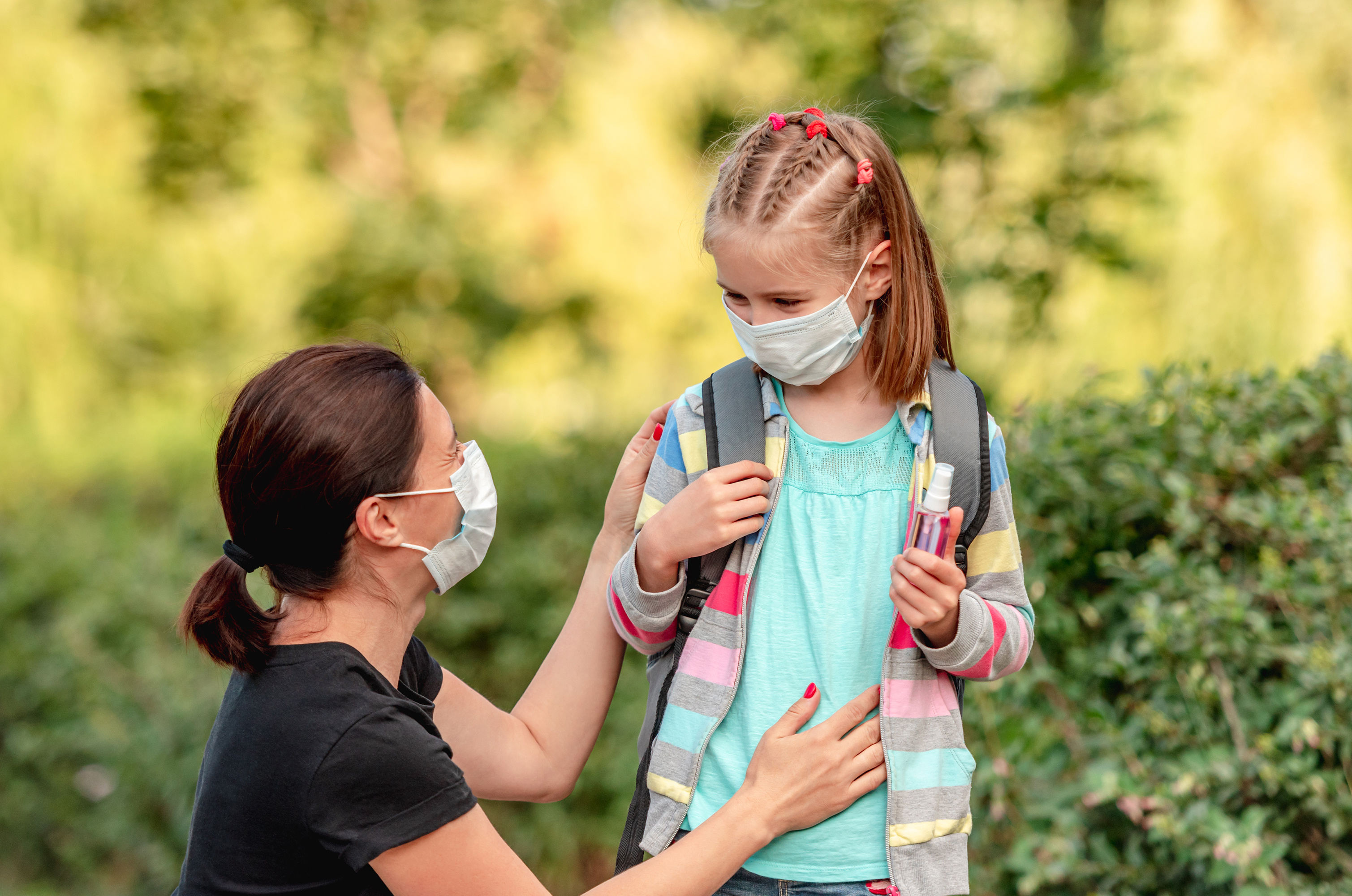 Mom walking young daughter back to school with a mask on