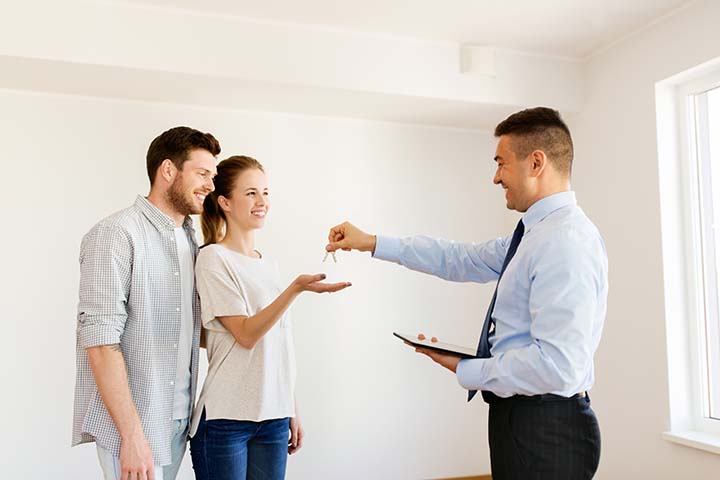caucasian couple receiving keys to a new home in an empty house
