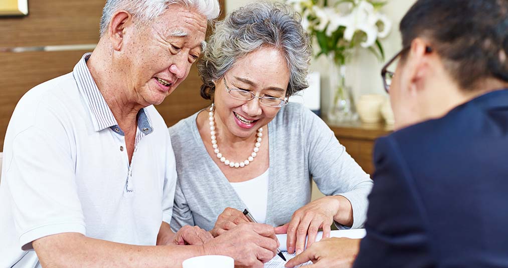 Couple signing life insurance policy when their insurance agent