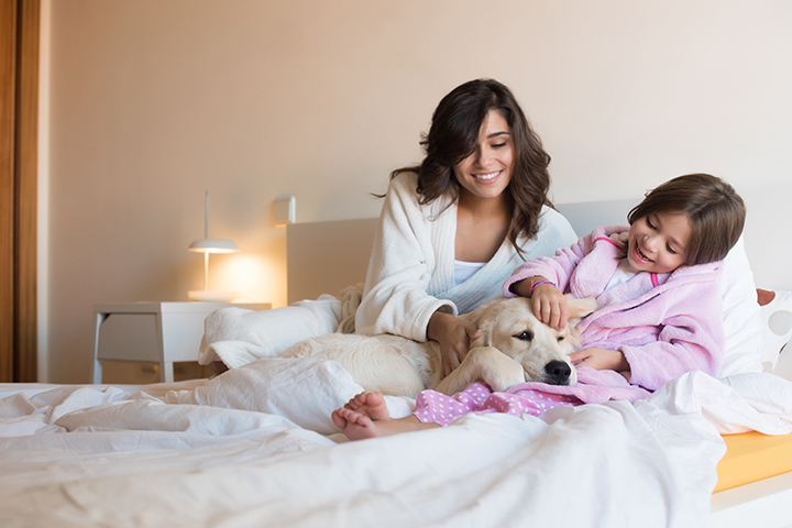 Mother and daughter playing with dog on the bed