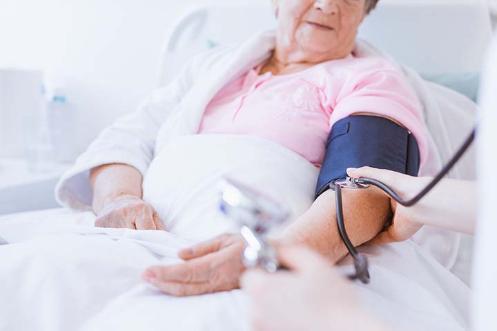 Woman having her blood pressure taken in hospital bed