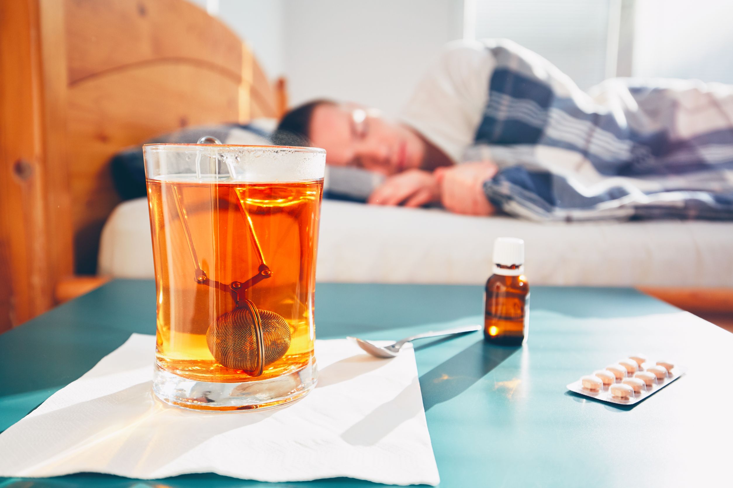 Man with pills and tea in bed sleeping