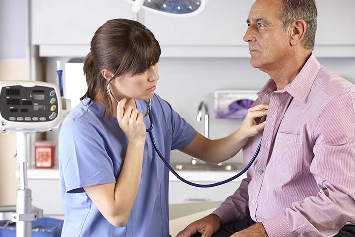 Elderly man getting  routine check-up at the doctor's office with a doctor listening to his heart and lungs with stethoscope