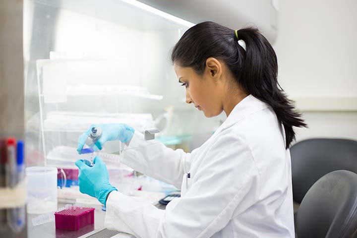 Científica que trabaja en un laboratorio con tubos de ensayo estudiando vacunas de ARNm
