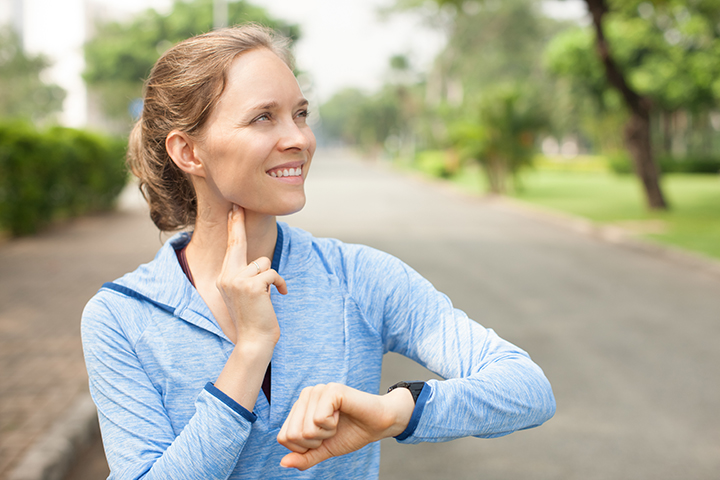 Woman running and checking her pulse using her neck.