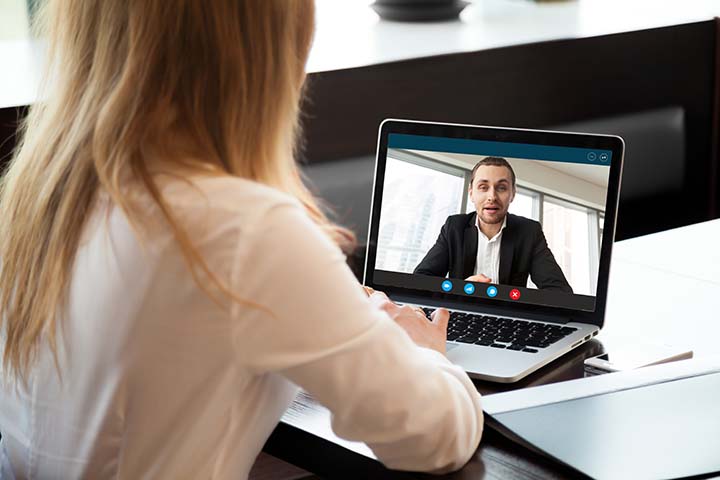 Woman with white blouse sitting through a virtual conference call with one other male coworker