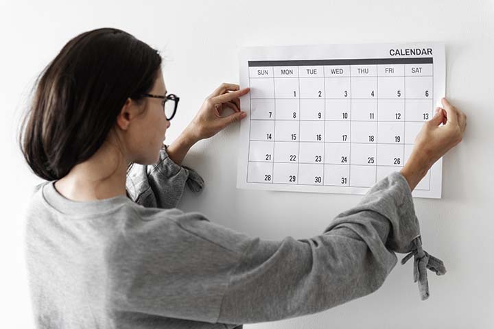 woman putting up a calendar made out of paper on the wall of her office