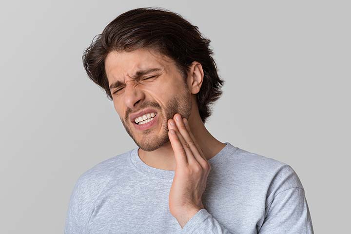 man with hand on the side of his cheek indicating toothache