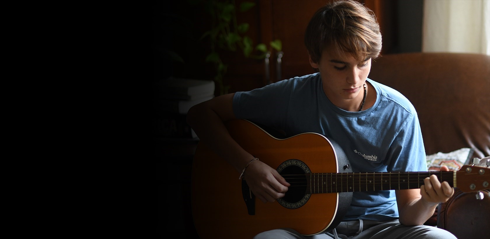 adolescente con camiseta azul tocando la guitarra